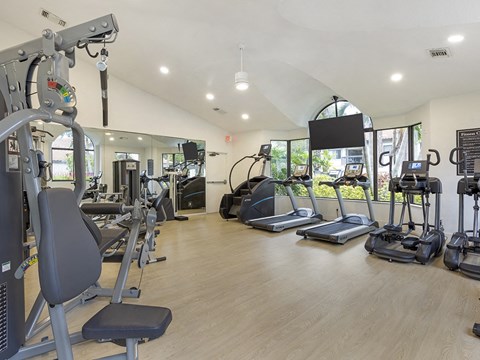 a gym with cardio equipment and weights on a wooden floor
